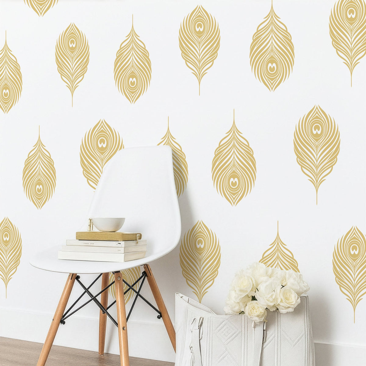 Gold peacock feather wall decals styled on a white wall above a modern chair and bouquet of roses