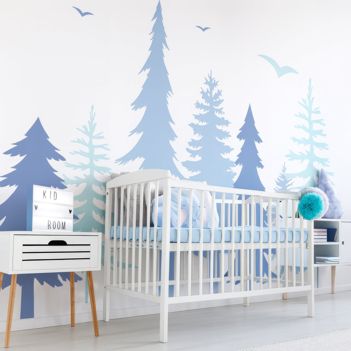 Pine forest wall decal arranged behind a crib in a soft nursery